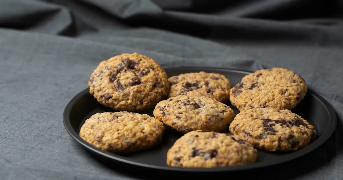 a plate of chocolate chip cookies on a gray cloth