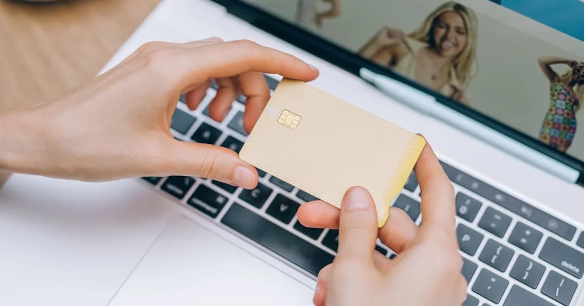 Close-up of hands holding credit card for online shopping on a laptop. Perfect for e-commerce and finance visuals.