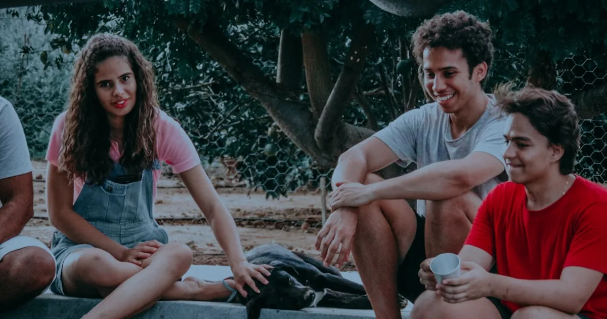 three men and one woman sitting on grey concrete floor