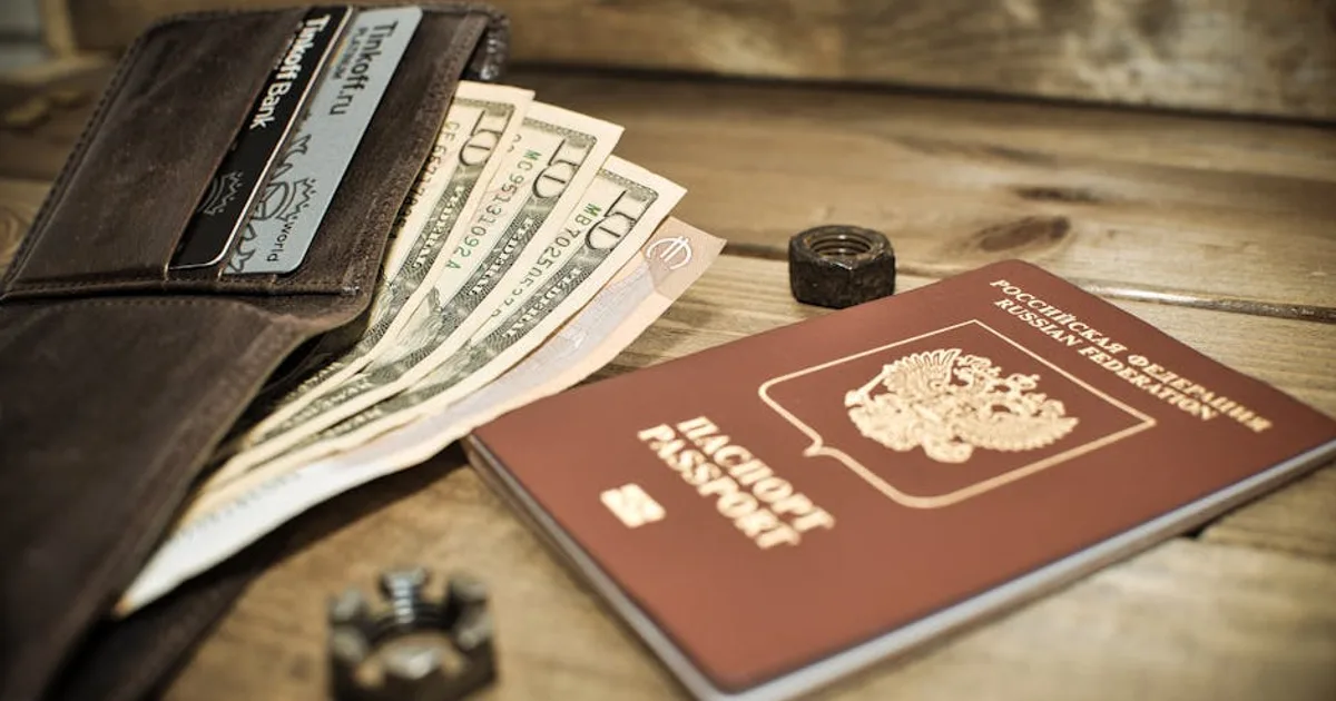 A wallet with cash, credit cards, and a Russian passport on a wooden table.