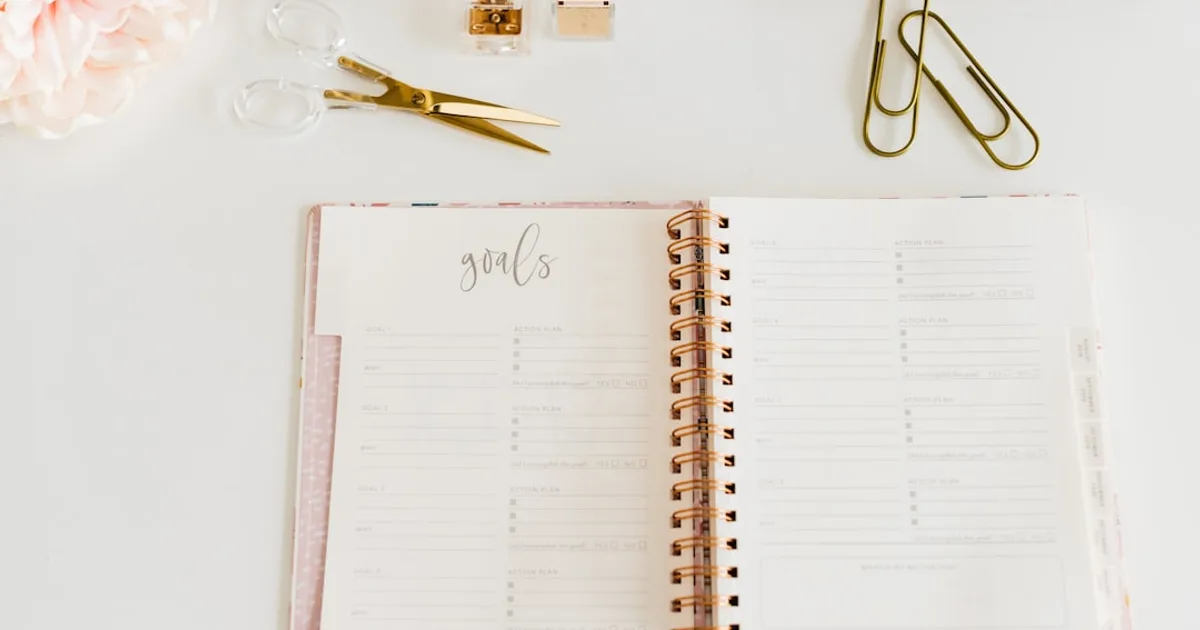 scissors and two paper clips beside opened spiral notebook
